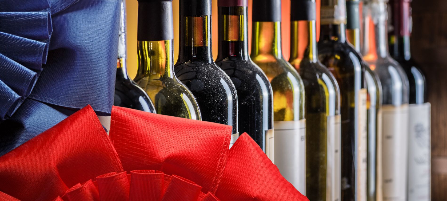 A row of wine bottles with portions of red and blue ribbons on the left side and corner.
