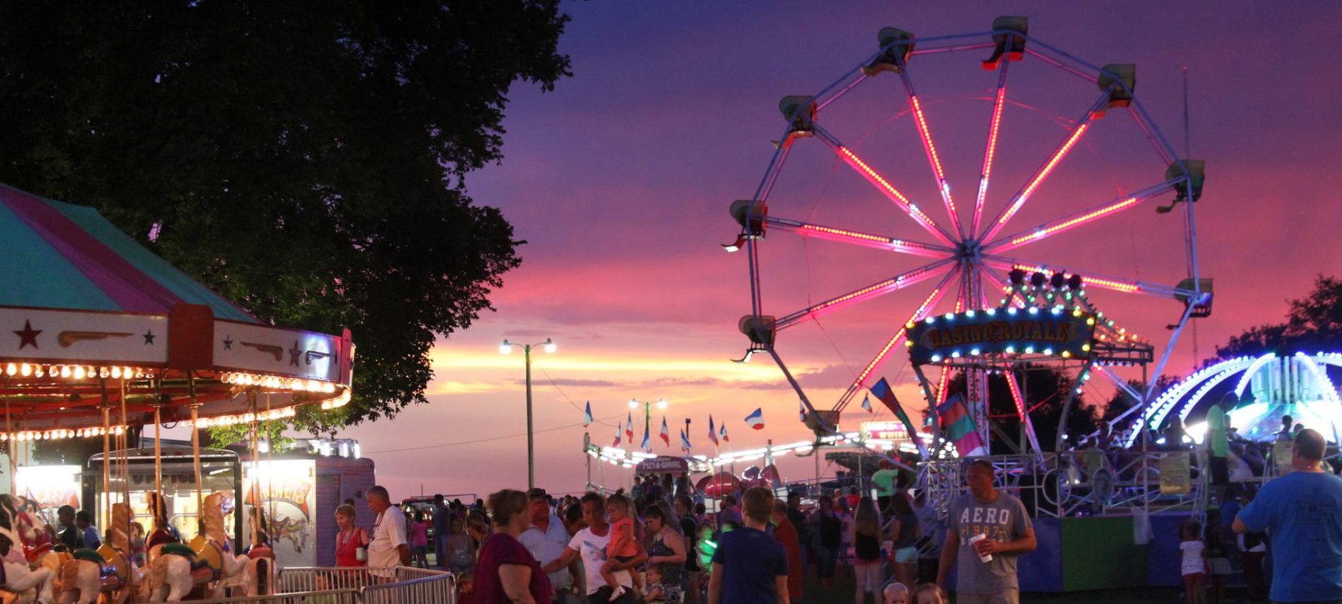 Sunset over Ferris wheel, merry-go-round and rides at the Clinton County Fair.