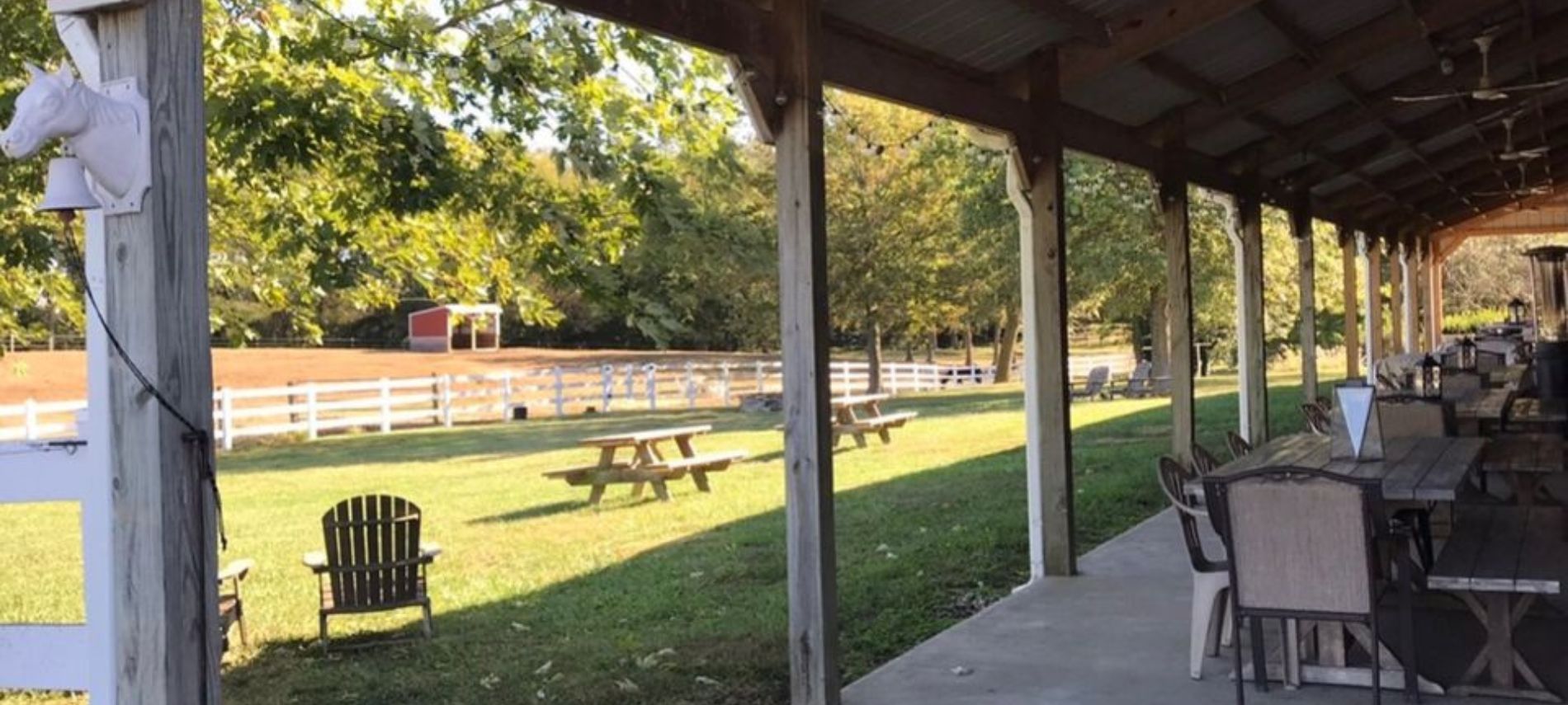 View of the patio at Crooked Creek with picnic tables, fence and horse pasture