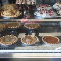 Clear glass bakery display case with variety of pies and cakes for sale.