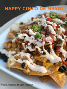 A platter of nachos with sour cream over the top.
